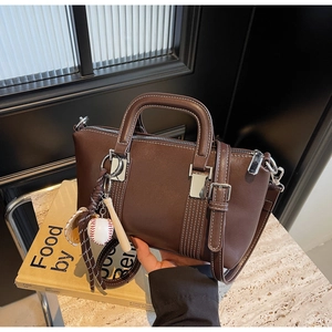 Détail de sac à main en cuir marron foncé avec coutures blanches et boucle argentée