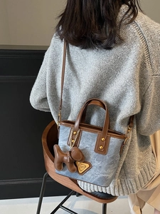 Sac seau bleu clair avec poignées en cuir marron et un joli pendentif en forme de chiot