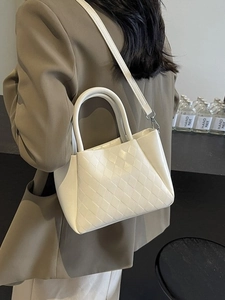 White woven crossbody tote bag with top handle shown on a model in a professional outfit