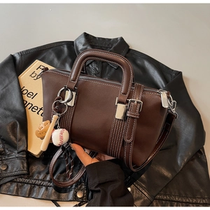 Détail du sac à main vintage marron avec breloque baseball et coutures blanches contrastées