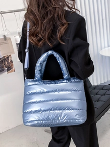 Hellblaue gesteppte Puffer-Umhängetasche mit Metallic-Effekt am Modell präsentiert