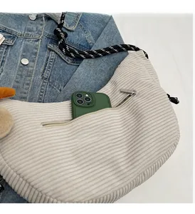 Detail of beige corduroy crescent bag with rope strap showing front zipper pocket capacity