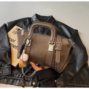 Gros plan sur un sac Boston marron foncé avec un pendentif unique sur le thème du baseball