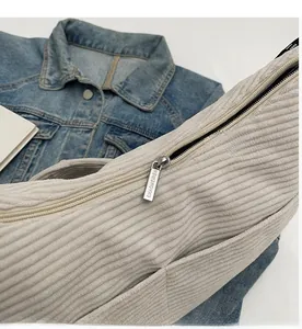 Detail of smooth metal zipper and thick corduroy texture on a beige hobo bag