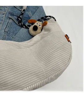 Detail view of beige corduroy crossbody bag with woven rope strap and plush dog charm