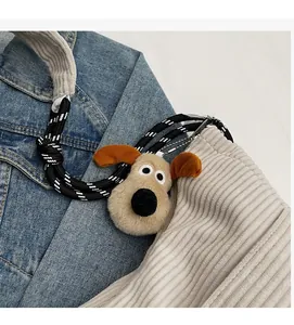 Detail of plush dog keychain with woven rope on corduroy and denim bag background