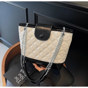 Detail of quilted texture on black and white tote bag with metallic chain strap