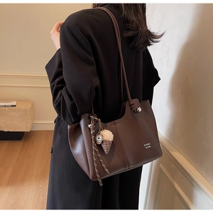 Detail of dark brown matte leather tote with braided rope and ice cream shaped charm