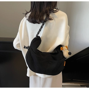 Detail of black corduroy hobo bag with striped rope strap and cute puppy pendant