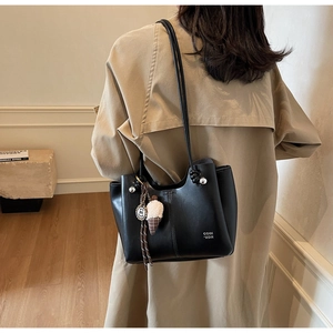 Close-up of black PU tote bag with COIM 2DM text and ice cream charm on model