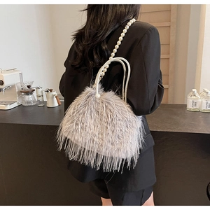 Detailed view of grey fuzzy bucket bag with pearl strap in a stylish cafe setting