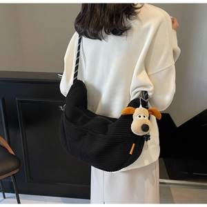 Rear view of model wearing a black corduroy dumpling crossbody bag with woven strap