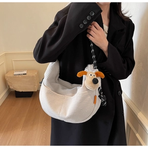 Close-up of cream corduroy crossbody bag featuring a plush puppy detail and braided strap
