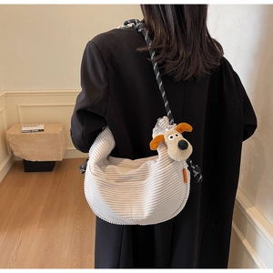 Detail of cream corduroy crossbody bag with cute dog pendant and woven strap