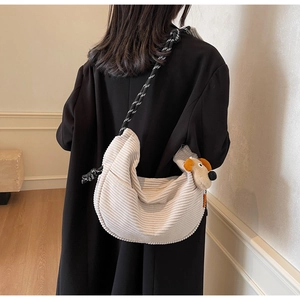 Detail of corduroy crossbody bag with woven strap and cute plush puppy charm
