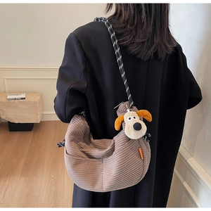 Brown corduroy crossbody bag with woven strap and cute puppy pendant on model back