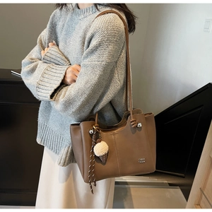 Detail of a brown tote bag with leather texture and a plush ice cream ball charm