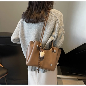 Brown faux leather tote bag detail with plush ice cream pendant and metal lettering