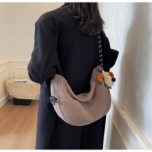 Brown corduroy crescent bag with plush dog charm and detailed vertical texture detail