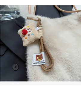 Dettaglio della borsa tote in peluche crema con ciondolo a stella e tracolla in corda