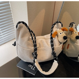 Detail of corduroy crossbody bag with woven strap and cute plush puppy charm