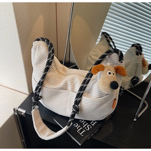 Detail of white corduroy tote bag featuring woven strap and cute puppy plush charm