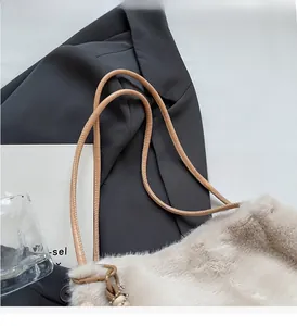Dettaglio borsa in peluche beige con tracolla marrone su uno sfondo alla moda