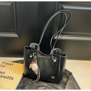 Detail of black leather tote bag with stylish ice cream pendant and metal logo accent