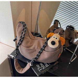 Detail view of brown corduroy hobo bag with thick woven strap and plush dog accessory