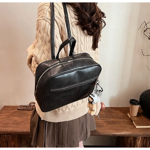 Close-up of black retro leather backpack with bear charm in cozy home setting