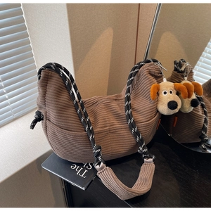 Detail of brown corduroy hobo bag with braided rope strap and cute puppy pendant