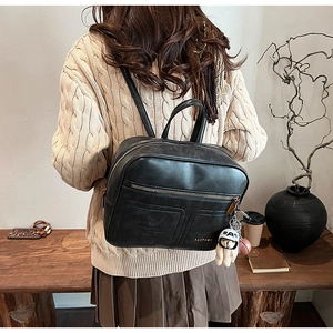 Detail of a vintage black PU leather backpack with teddy bear charm and PANTOUR logo