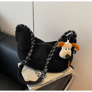 Detail of black corduroy crescent bag featuring woven rope strap and plush charm