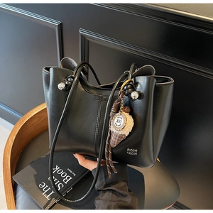 Detail of black tote bag with knotted handles, silver beads and a plush ice cream charm