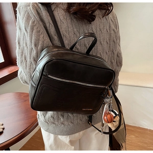 Detail view of black faux leather backpack with metallic zipper and cute charms
