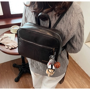 Detail of black synthetic leather backpack with stylish bear and basketball charms
