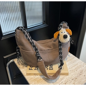 Detail of brown corduroy tote bag with woven strap and cute plush dog pendant charm