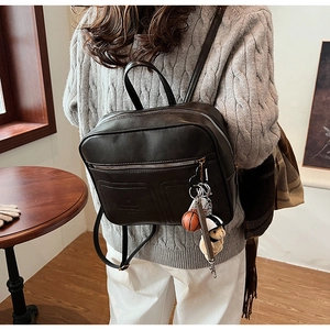 Detail of vintage faux leather backpack featuring textured finish and embossed pocket logo
