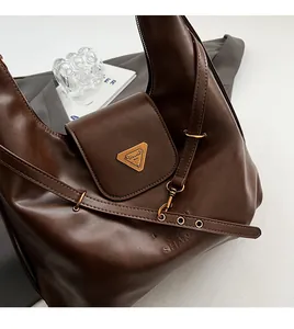 Detail of dark brown leather tote bag with gold triangle logo and adjustable strap