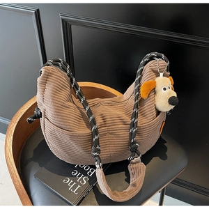 Detail of corduroy crossbody bag featuring a thick rope strap and cute puppy plush charm