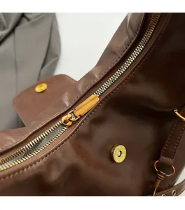 Detail of smooth gold zipper and high-quality dark brown leather texture on tote bag