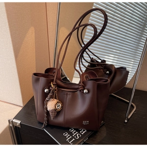 Detail of dark brown tote bag showing silver bead decor and coin charm accessory