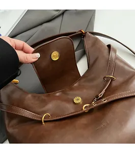 Close-up of vintage dark brown leather bag showing magnetic clasp and textured finish