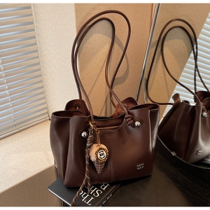 Detail of dark brown tote bag with ice cream charm and knotted silver bead strap