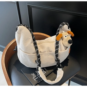 Detail of corduroy crossbody bag featuring a woven rope strap and plush dog pendant