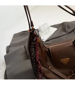 Detail of vintage dark brown leather tote with metallic triangle logo and key charm