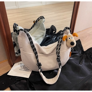Detail of off-white corduroy crescent bag with woven rope strap and plush gromit charm