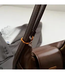 Close-up of golden metal ring hardware and fine stitching on dark brown leather bag