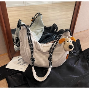 Detail of off-white corduroy crescent bag with stylish woven rope strap and dog charm