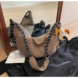 Detail of a brown corduroy crescent bag with braided rope strap and plush puppy charm